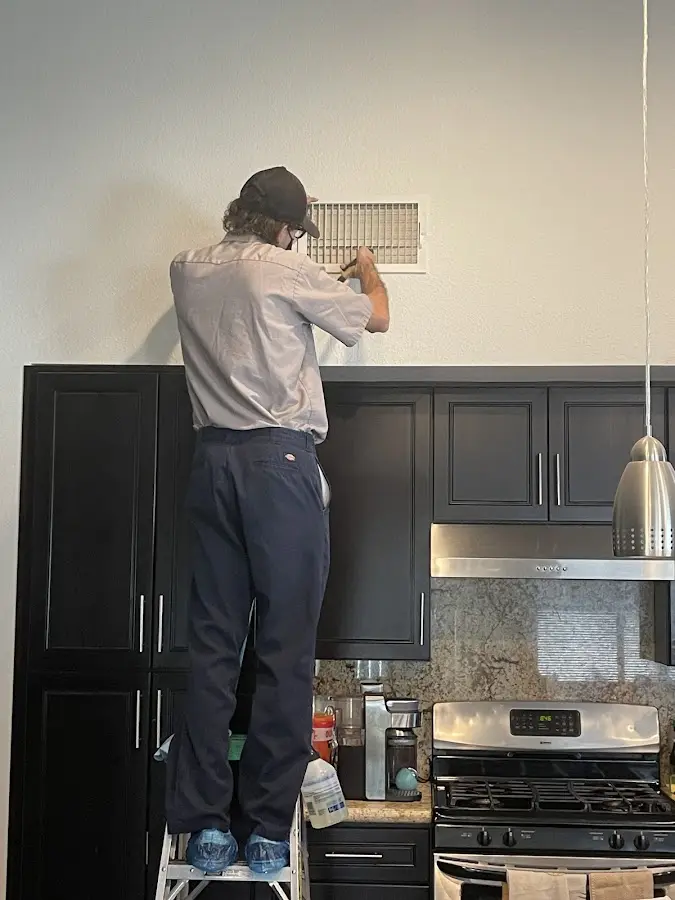 Technician inspecting an air vent during HVAC service in Kapolei